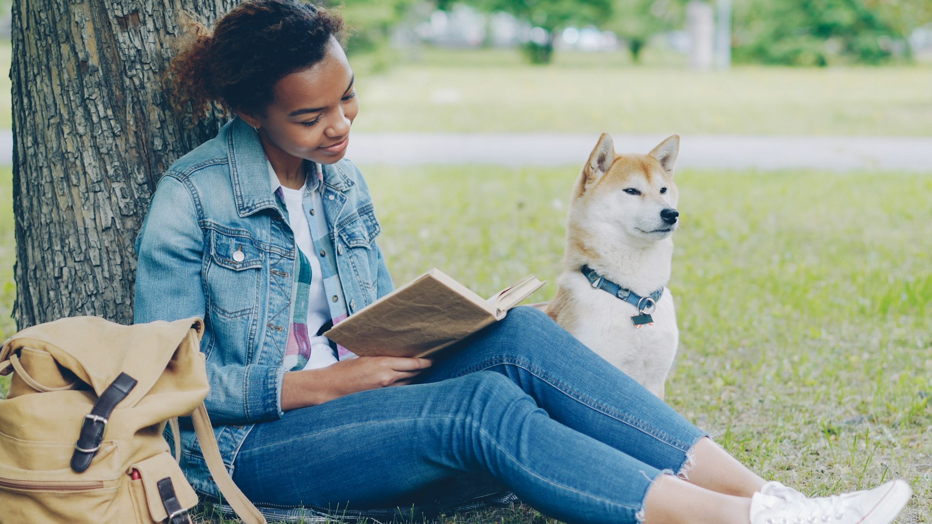 Girl reads a book with her dog.